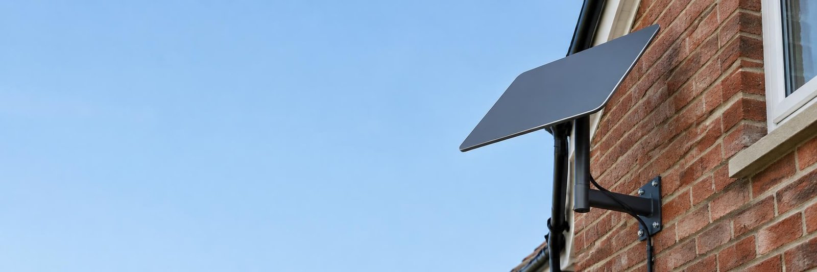 Starlink dish on a wall bracket on a brick house